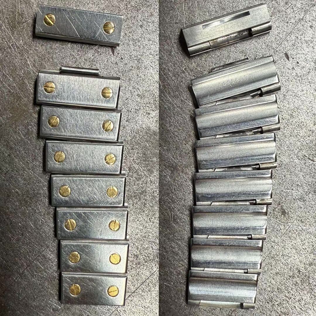 Una vista divisa che mostra entrambi i lati di nove maglie rettangolari in metallo del cinturino di un orologio, fissate con viti color ottone.