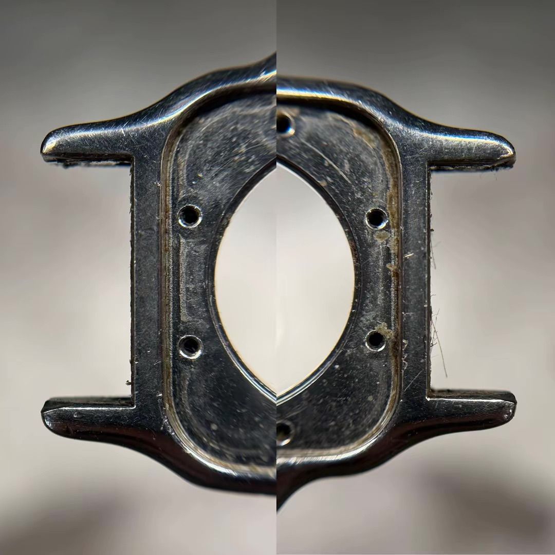 Una vista ravvicinata e speculare della cassa di un orologio in metallo nero, con quattro fori per le viti e anse visibili su entrambi i lati.