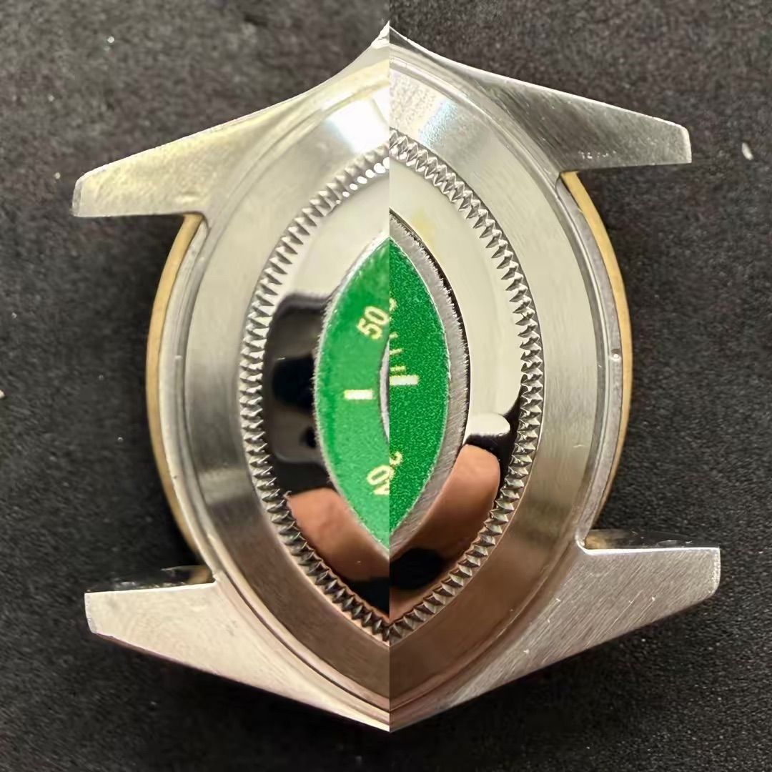 Il fondello di una cassa di orologio in metallo lucido presenta un inserto centrale verde con indici numerici, riprodotti simmetricamente.