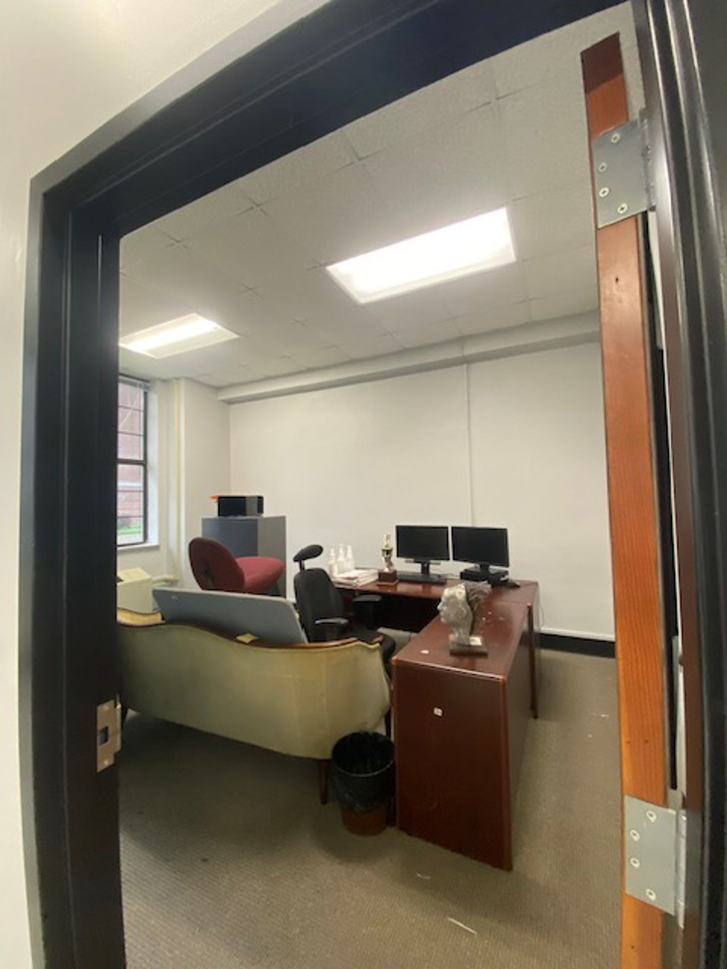 Office cubicle with a desk, computer monitors, and a chair, seen through an open doorway.