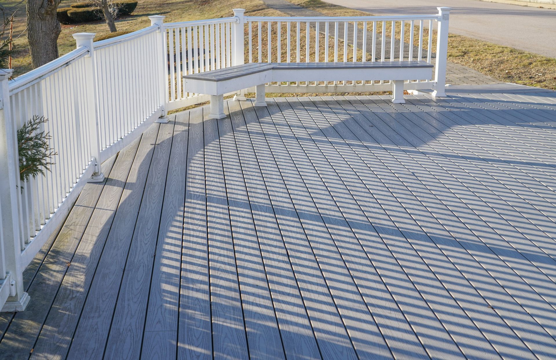 A wooden deck with a white railing and a bench