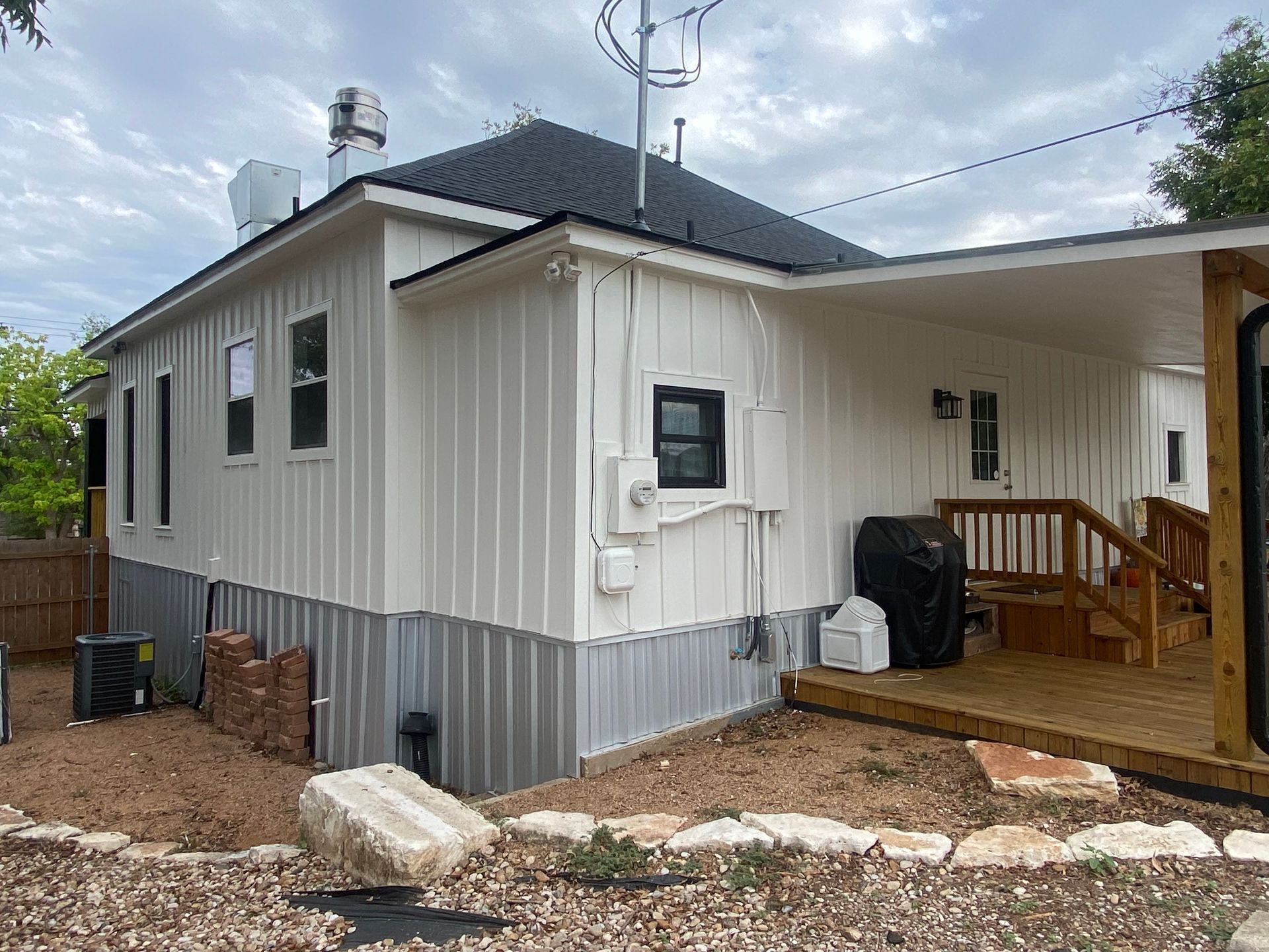 The back of a white house with a porch and stairs.