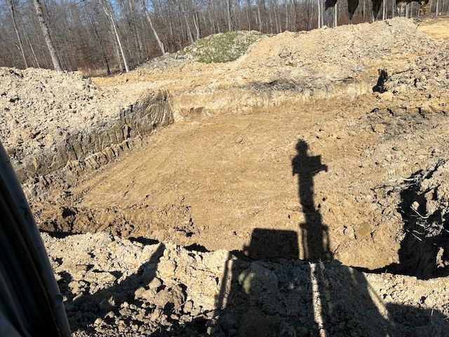 Excavation site with large piles of dirt and a shadow of a person operating machinery.