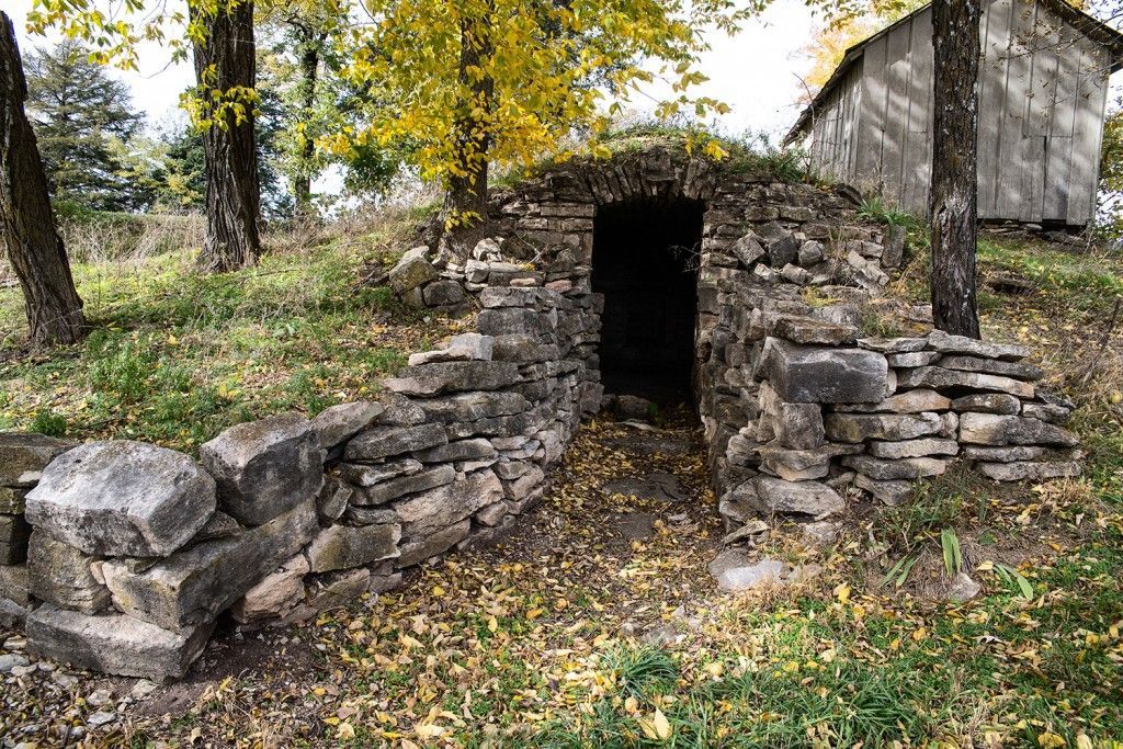 A stone wall with a door in the middle of a forest.