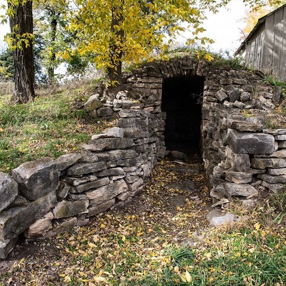 A stone wall with a door in the middle of it surrounded by trees.