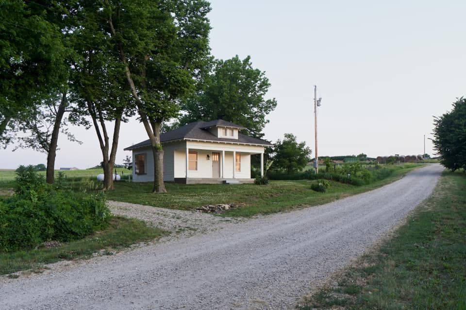 A small house sits on the corner of a dirt road