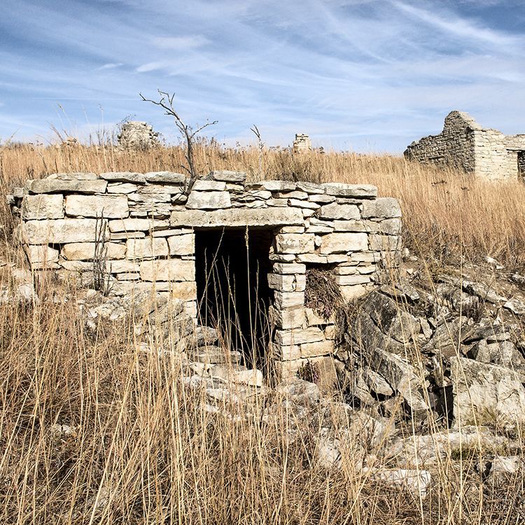 An old stone building is sitting in the middle of a field.