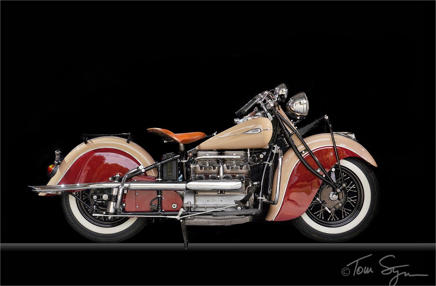 Classic two-tone Indian motorcycle against a black backdrop, featuring white-wall tires and a tan and red color scheme.