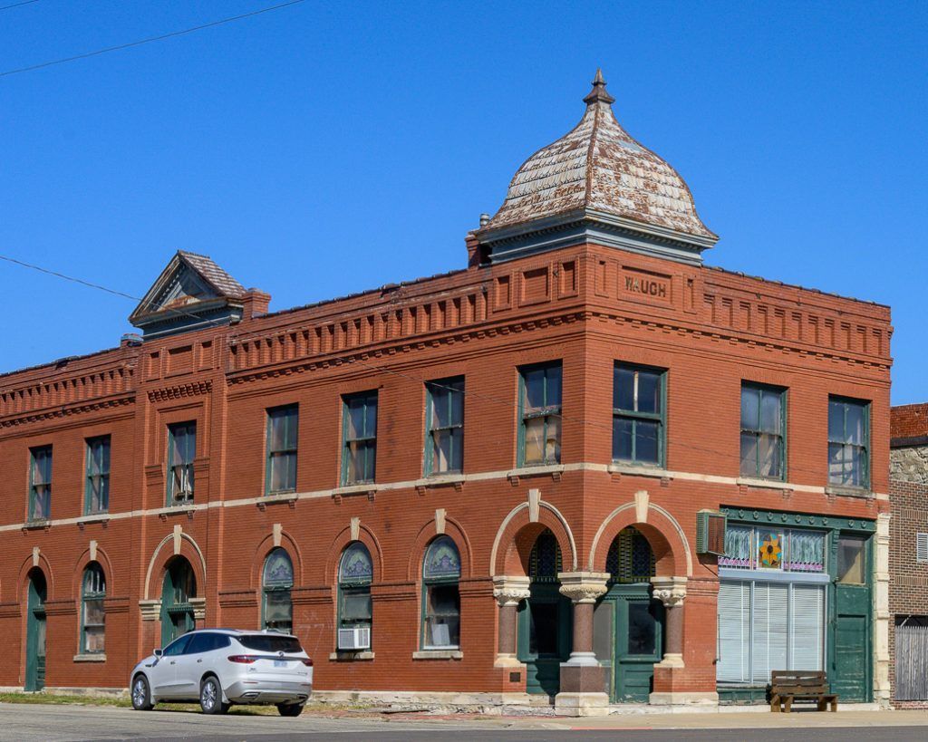 Red brick building with arched windows, a domed roof, and a parked car.