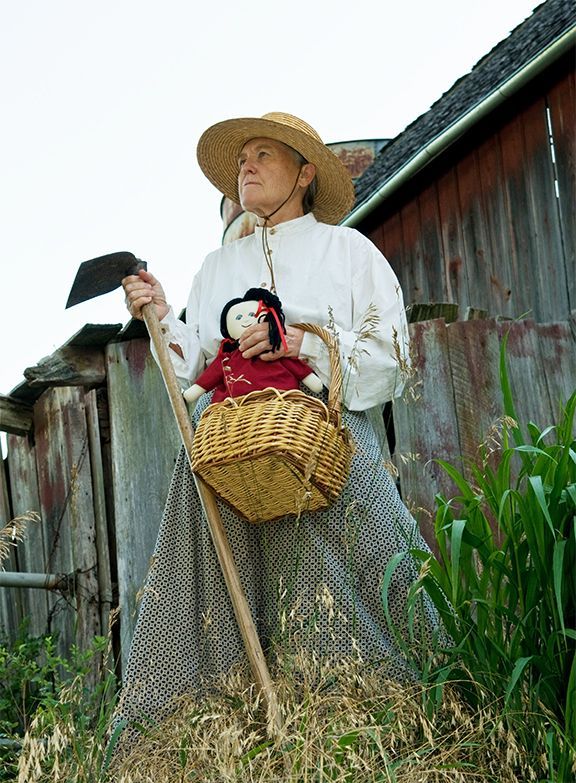 A woman in a straw hat is holding a doll in a basket.