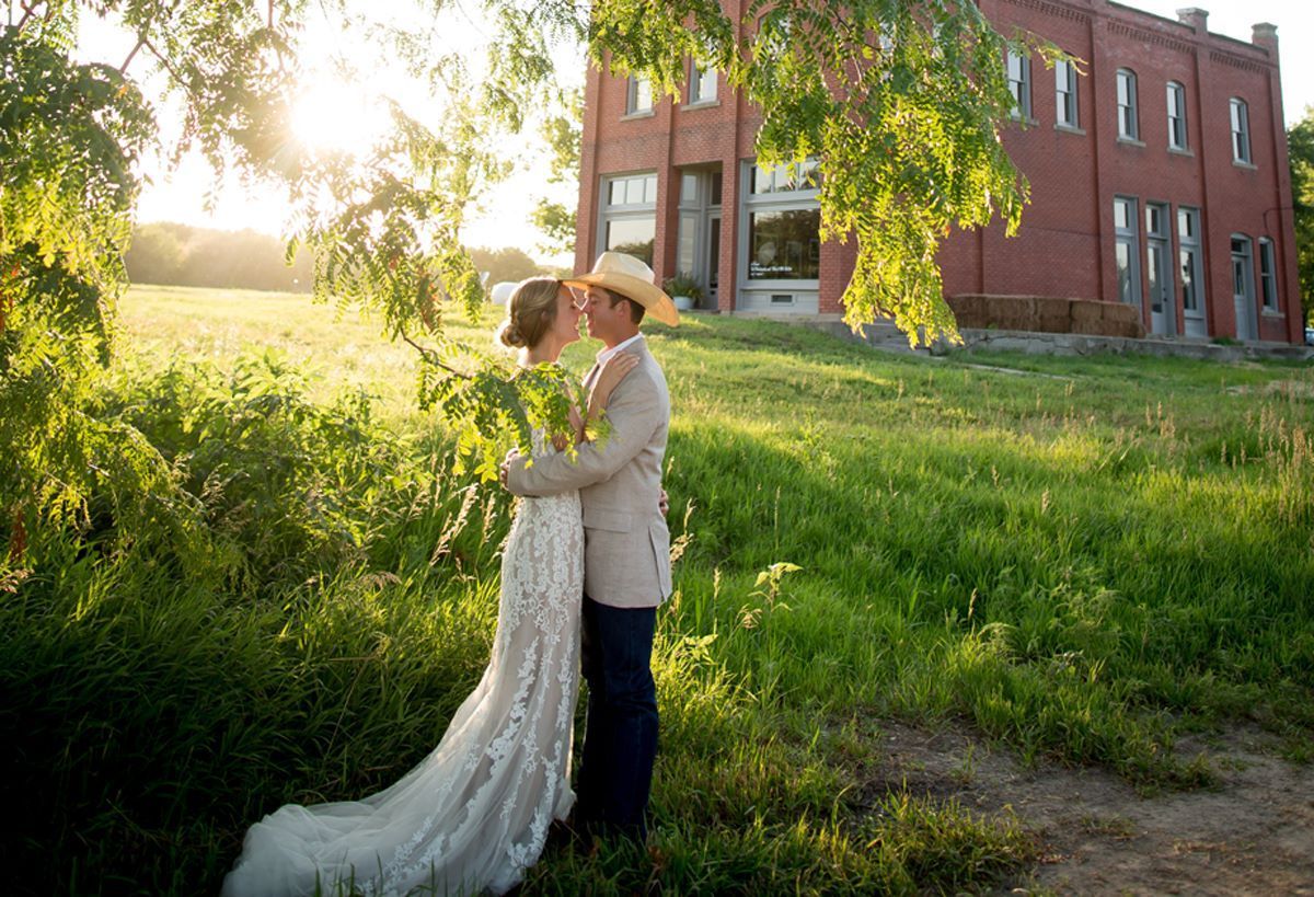 A bride and groom are kissing in front of a brick building.