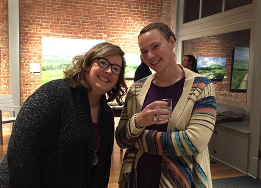 Two women are posing for a picture in front of a brick wall.