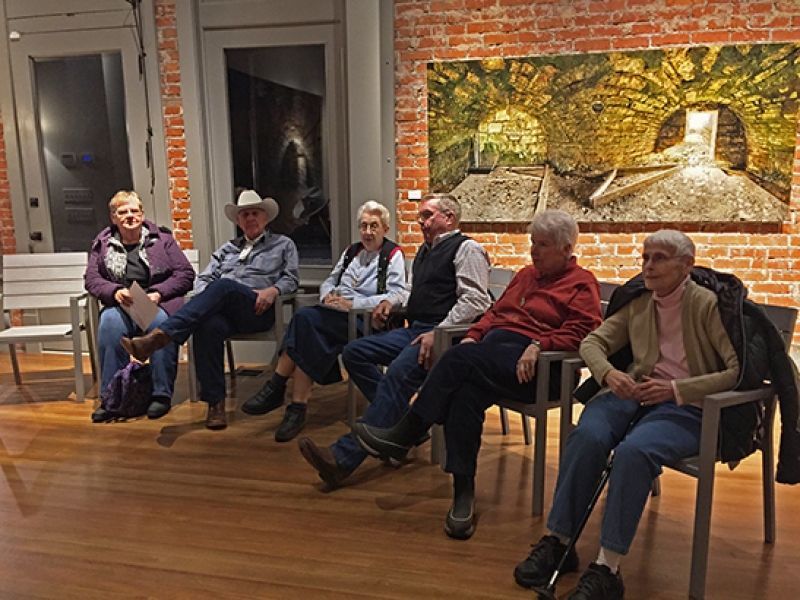 A group of people are sitting in chairs in front of a brick wall.
