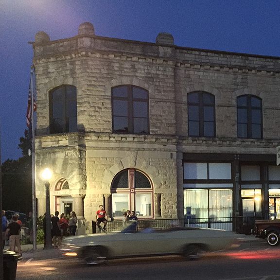 A car is driving past a brick building at night