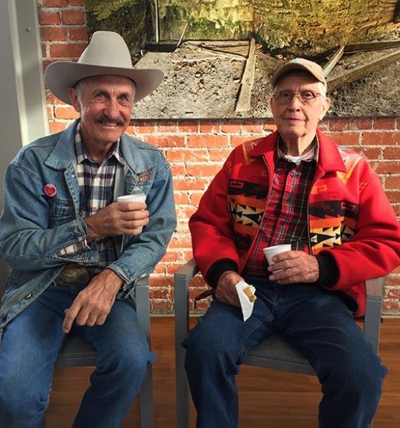Two men are sitting next to each other in front of a brick wall
