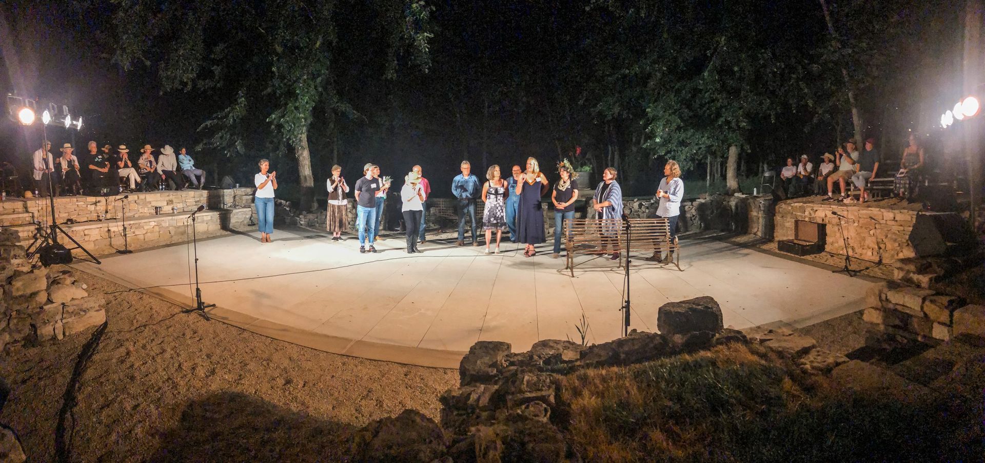 People performing on a stage at night. Audience on the side.