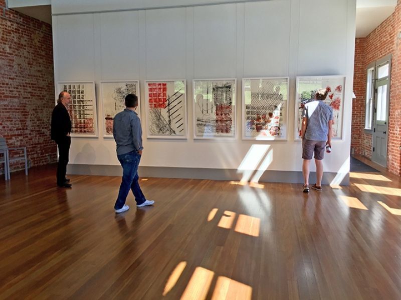Two men are looking at paintings in a museum.