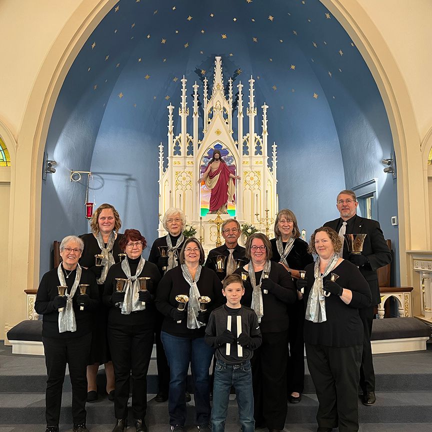 Group of people with handbells posing in front of a church altar.