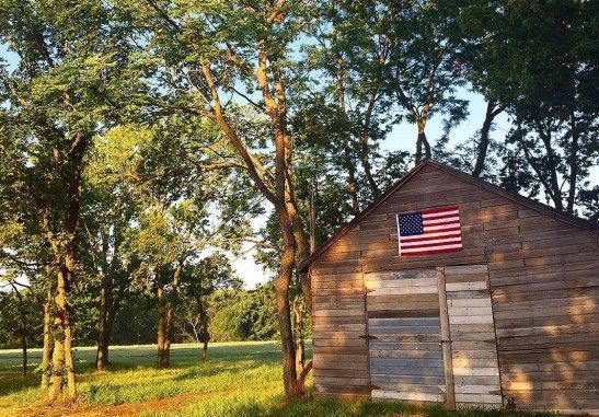 An old wooden barn with an american flag on the roof.