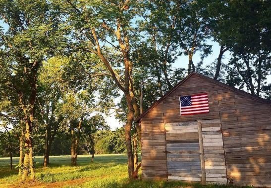A wooden shed with an american flag on the side of it.