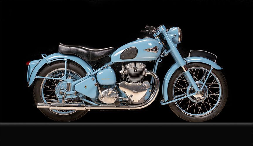 Light blue vintage Royal Enfield motorcycle against a black backdrop.