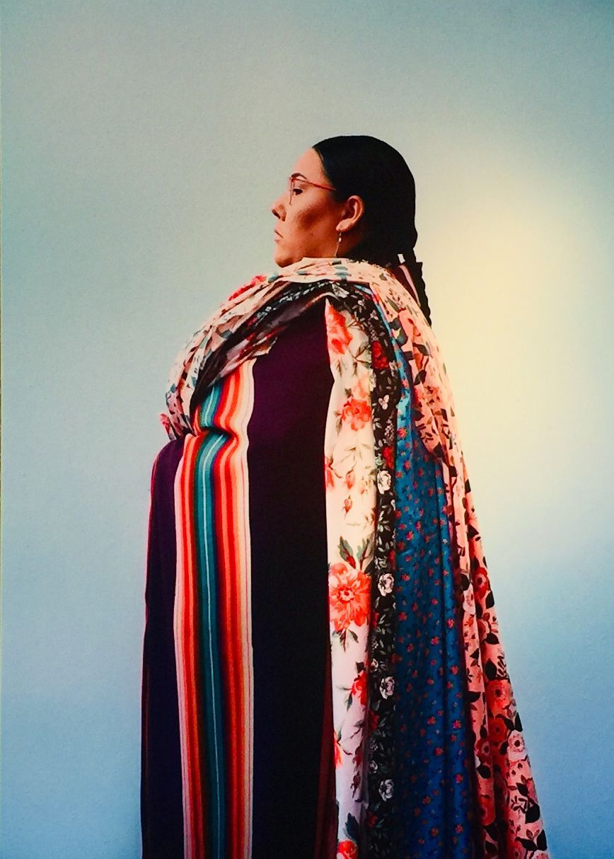 Woman in colorful shawl, profile view. Blue background.