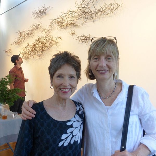 Two women posing for a picture with a man in the background