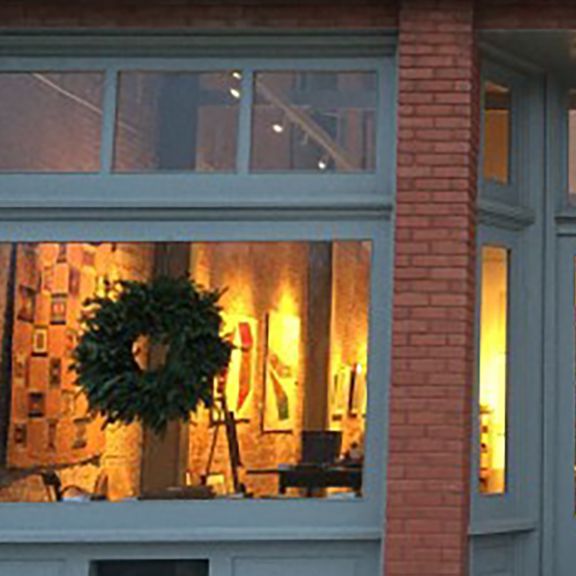 Exterior of art gallery with wreath in window, brick pillar.
