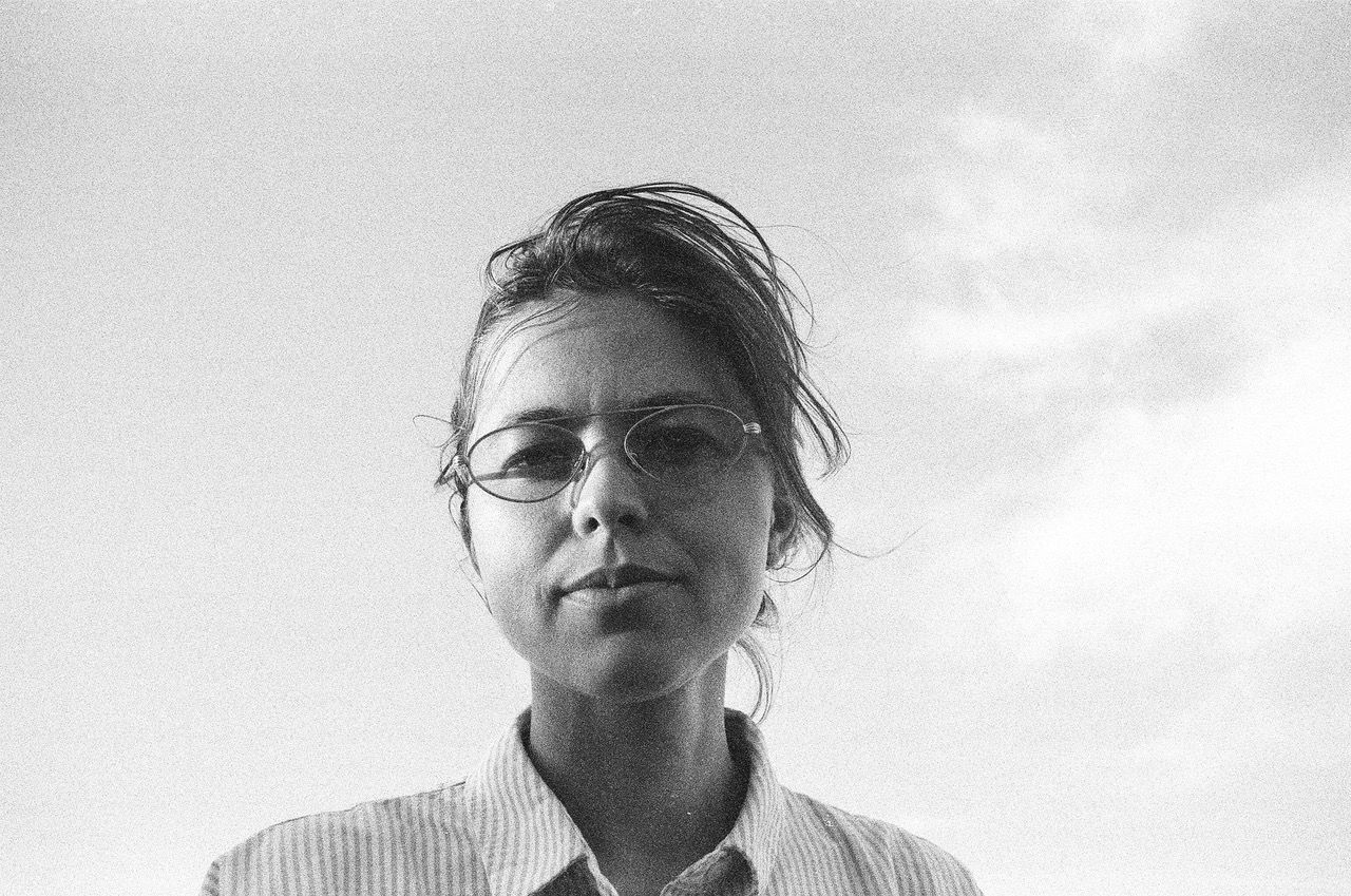 A black and white photo of a woman wearing glasses and a striped shirt.