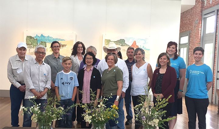 A group of people are posing for a picture in front of a painting.