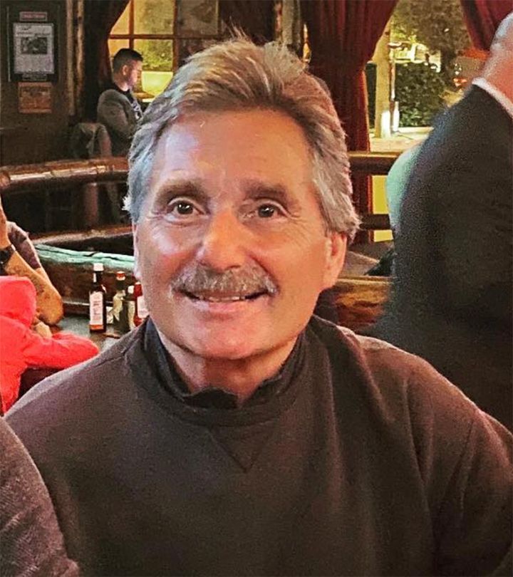 A man with a mustache is smiling in a bar.
