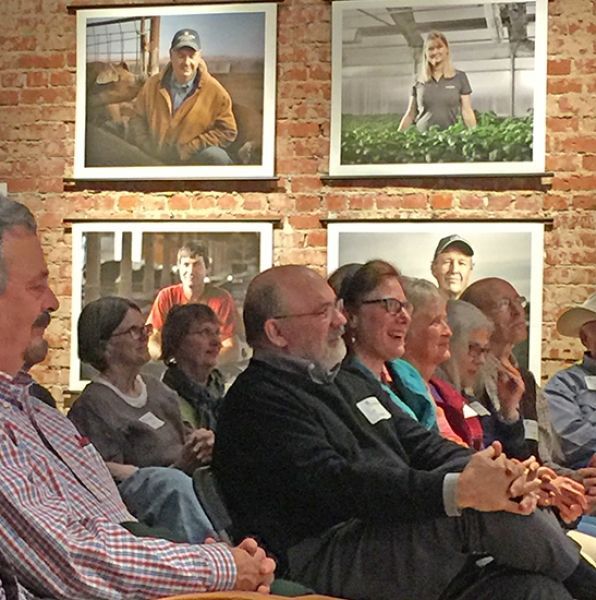 A group of people are sitting in front of a wall with pictures on it
