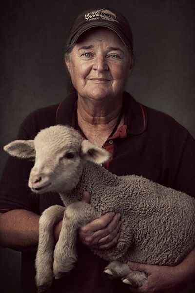 A man in a hat is holding a baby sheep