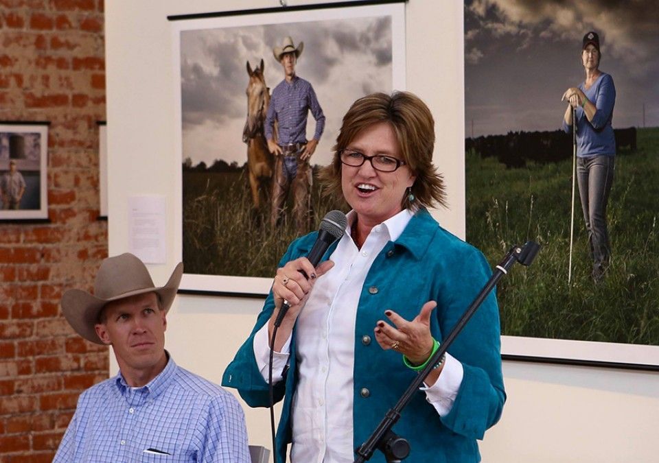 A woman in a blue jacket is speaking into a microphone