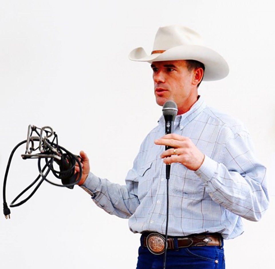 A man in a cowboy hat is holding a microphone