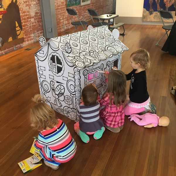 A group of children are playing with a cardboard house