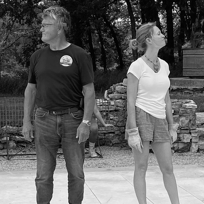 Man and woman looking off to the side, outside. Man in jeans and shirt; woman in shorts and top.