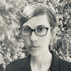 A black and white photo of a woman wearing glasses.