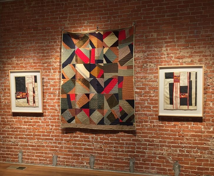 A brick wall with a quilt hanging on it