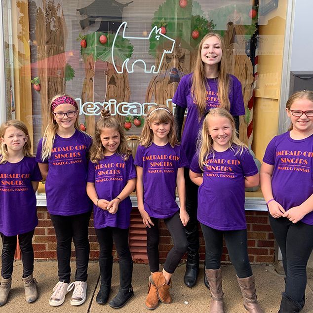 A group of young girls wearing purple shirts are posing for a picture