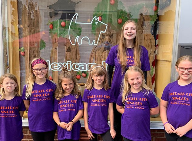 A group of young girls wearing purple shirts are posing for a picture