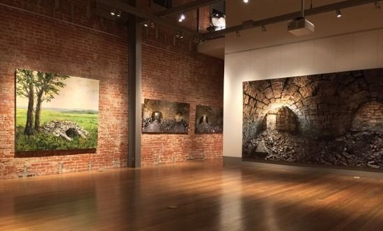 A large empty room with a wooden floor and paintings on the walls.