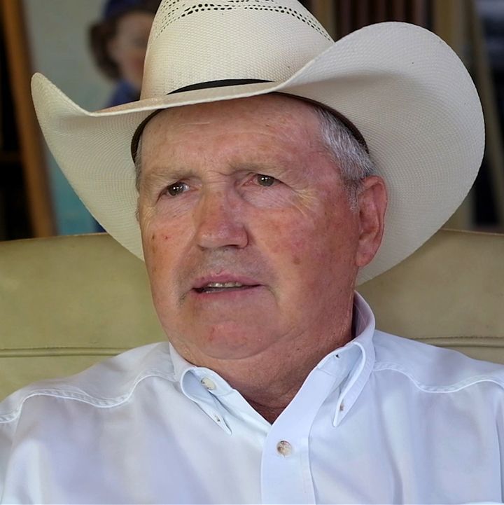 Man in cowboy hat and white shirt; seated.