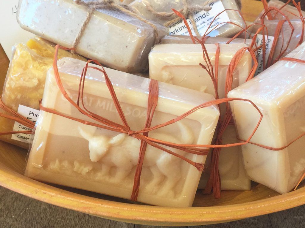 Soaps in a wooden bowl, wrapped with raffia. Some bars have goat molds.