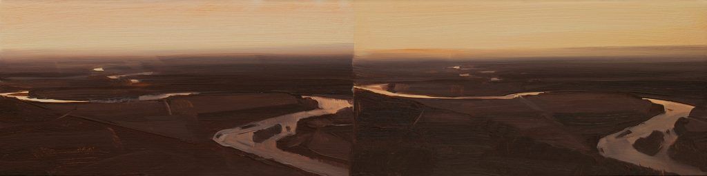 An aerial view of a river flowing through a forest at sunset.