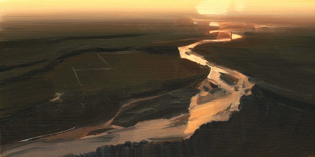 An aerial view of a river flowing through a forest at sunset.