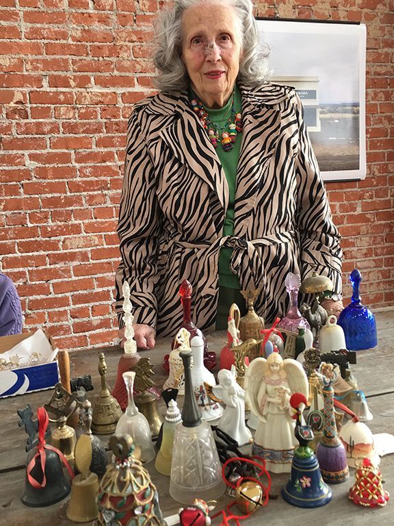 A woman is standing in front of a table full of bells