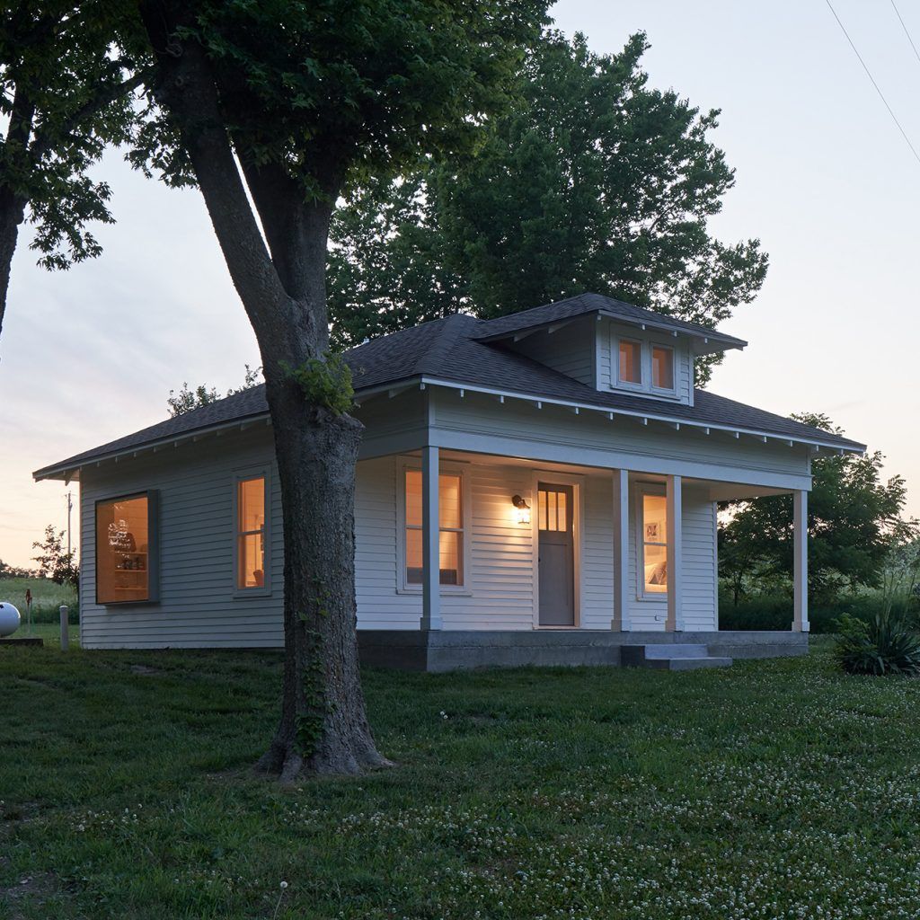 A small white house with a tree in front of it