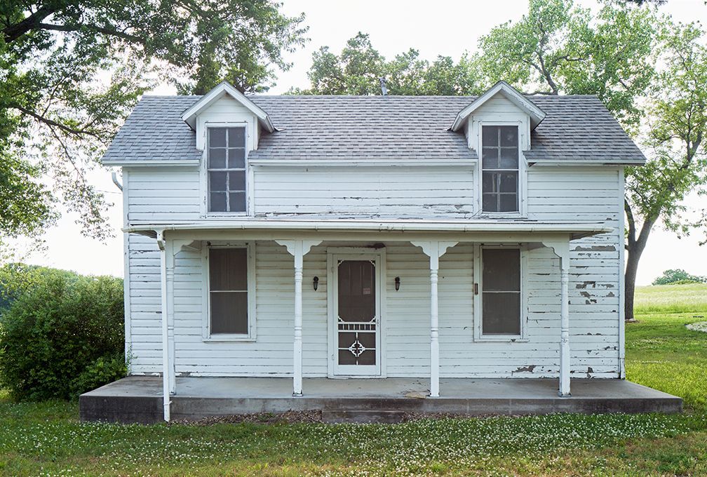 A small white house with a screened in porch