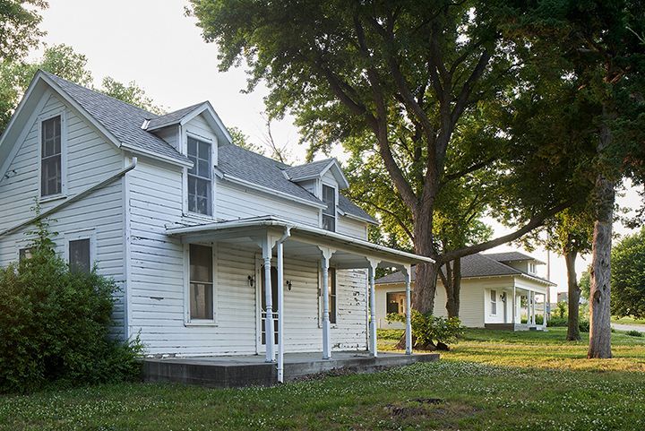 A white house with a porch and trees in front of it